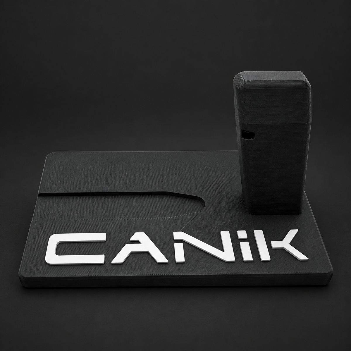 Front view of black Canik Mete Series and TT Combat polymer display stand with raised white CANIK lettering on a charcoal background