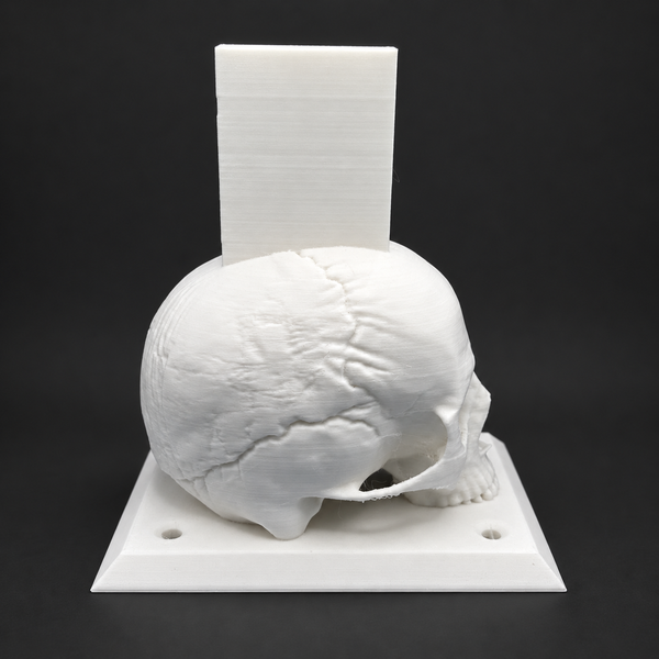 White VWcustomworks Skull Rifle Stand on a square base with upright magwell support, shown alone against a dark background.